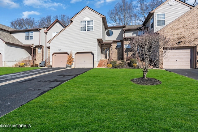 view of front of house with a front yard, a garage, brick siding, and driveway