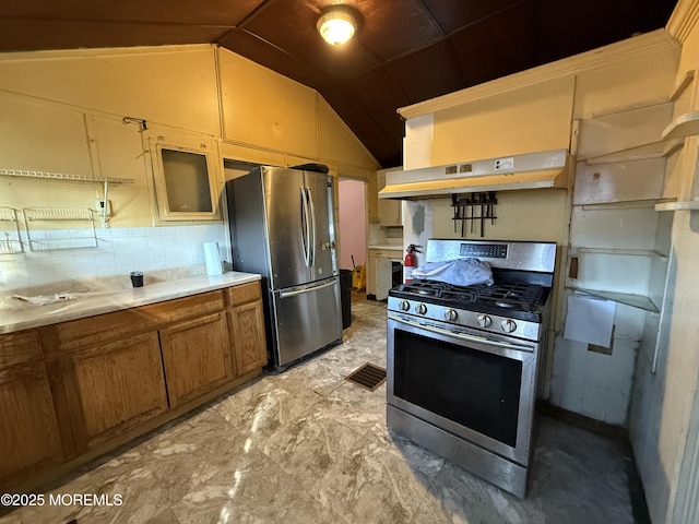 kitchen with light countertops, appliances with stainless steel finishes, brown cabinetry, vaulted ceiling, and under cabinet range hood