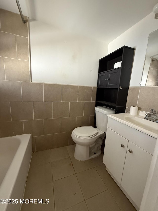 full bath featuring tile patterned flooring, toilet, a wainscoted wall, vanity, and tile walls