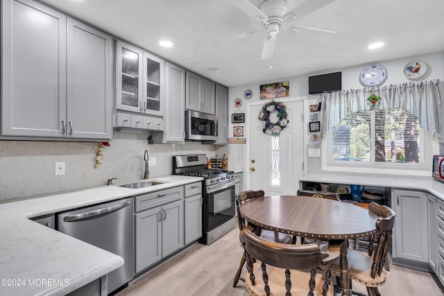 kitchen featuring gray cabinetry, stainless steel appliances, a sink, light wood-style floors, and light countertops