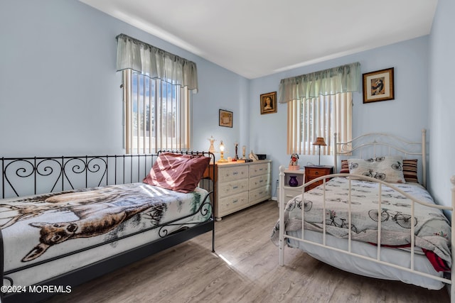 bedroom with multiple windows and wood finished floors