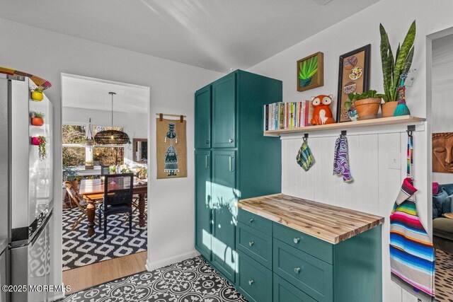 interior space featuring butcher block counters, green cabinets, light wood-type flooring, freestanding refrigerator, and open shelves