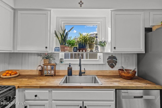 kitchen featuring dishwasher, butcher block counters, white cabinets, and a sink