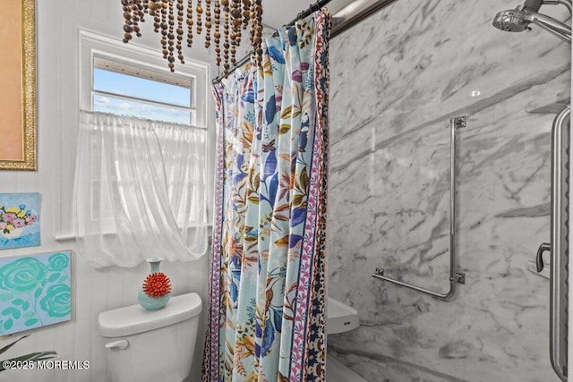 bathroom featuring toilet and a marble finish shower