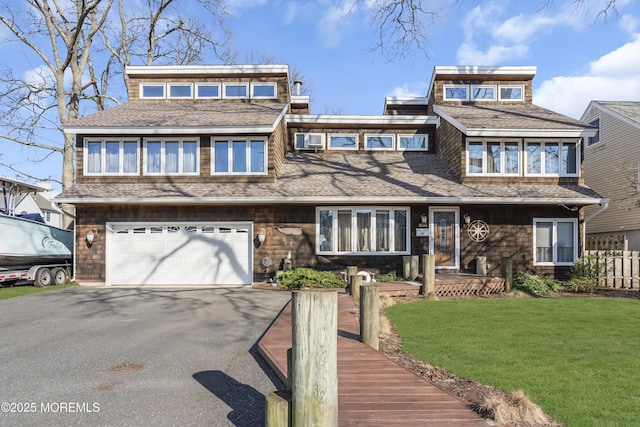 view of front facade featuring driveway, roof with shingles, an attached garage, and a front yard