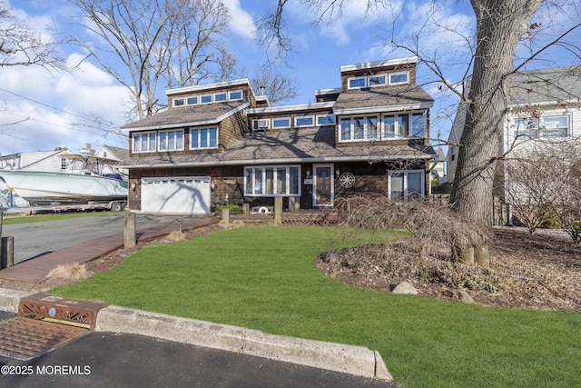 view of front of home featuring driveway, a garage, and a front yard