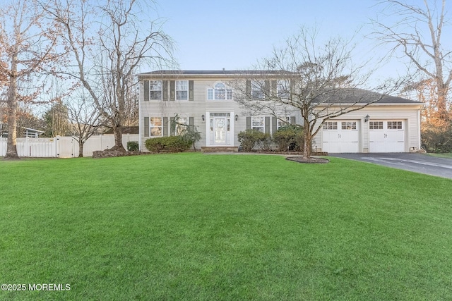 colonial-style house with a garage, driveway, a front lawn, and fence