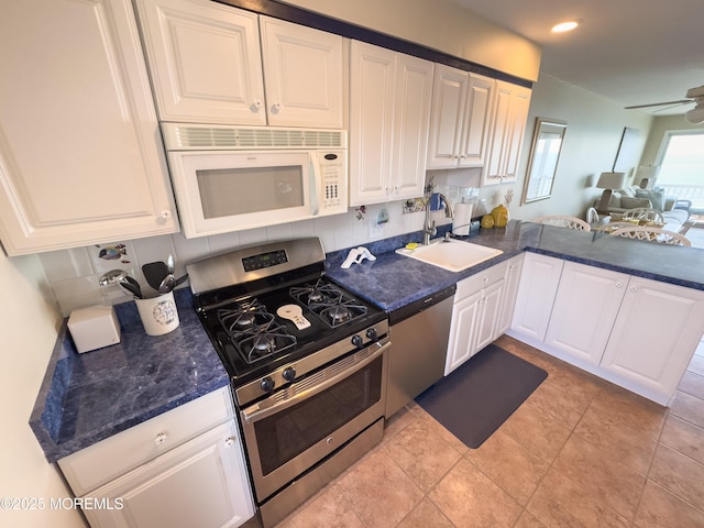 kitchen featuring ceiling fan, appliances with stainless steel finishes, open floor plan, white cabinetry, and a sink