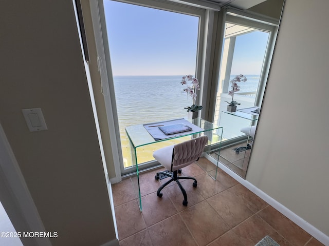 tiled home office with baseboards, a water view, and a healthy amount of sunlight