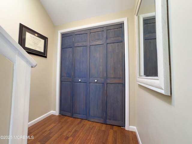 unfurnished bedroom with dark wood-style flooring, a closet, and baseboards