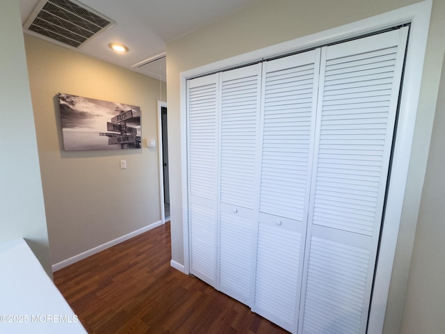 corridor featuring dark wood-style floors, attic access, visible vents, and baseboards