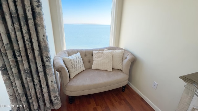 sitting room featuring a water view, baseboards, and wood finished floors