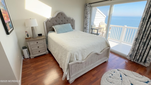 bedroom with dark wood-type flooring and a water view