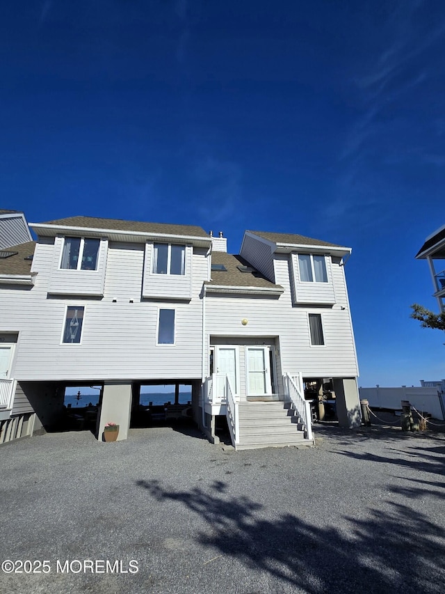 view of front of property with a carport, roof with shingles, and driveway