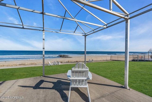 view of patio / terrace featuring a water view, fence, and a view of the beach