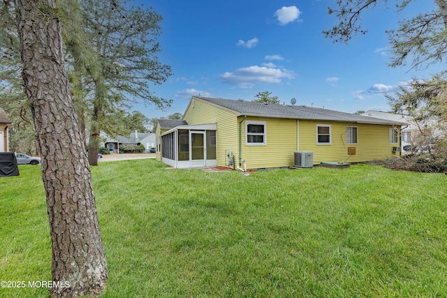 rear view of house featuring a sunroom, a lawn, and central air condition unit