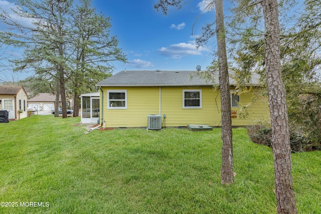 back of house featuring a shingled roof, a sunroom, crawl space, a yard, and central AC