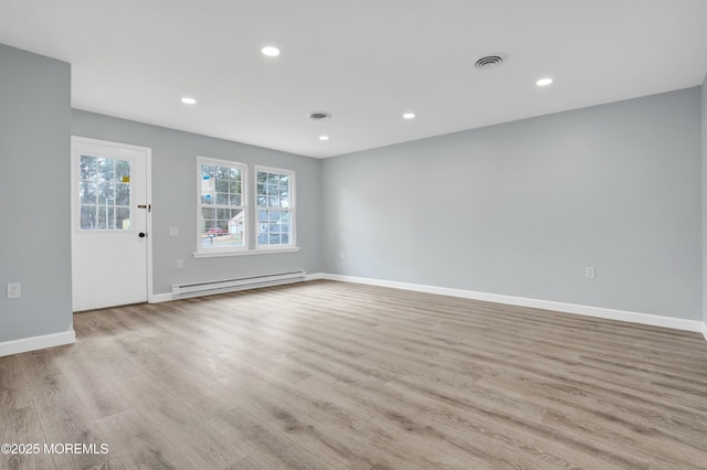 interior space featuring recessed lighting, visible vents, a baseboard heating unit, light wood-style floors, and baseboards