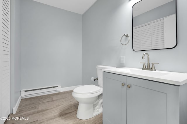 bathroom with toilet, a baseboard heating unit, vanity, wood finished floors, and baseboards