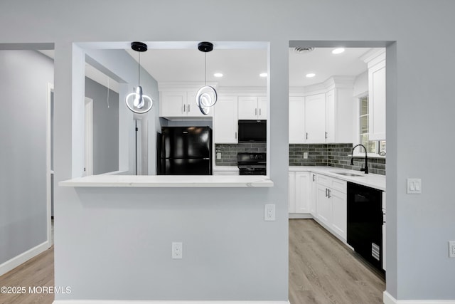 kitchen featuring hanging light fixtures, black appliances, a kitchen island, and light countertops