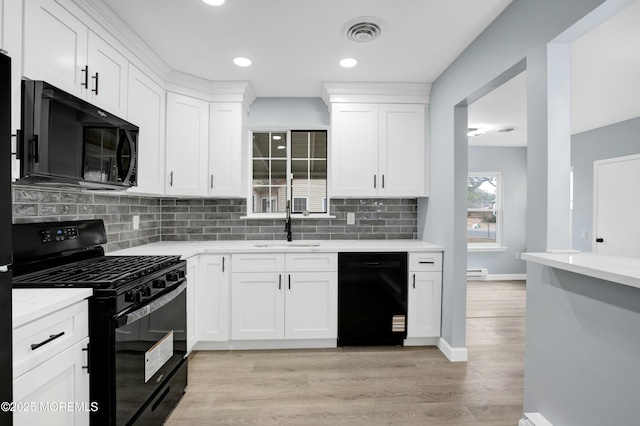 kitchen featuring visible vents, white cabinets, light wood-style floors, black appliances, and a sink