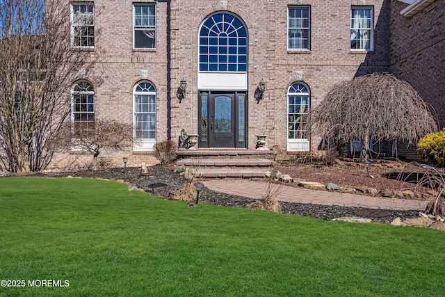 property entrance featuring a yard and brick siding