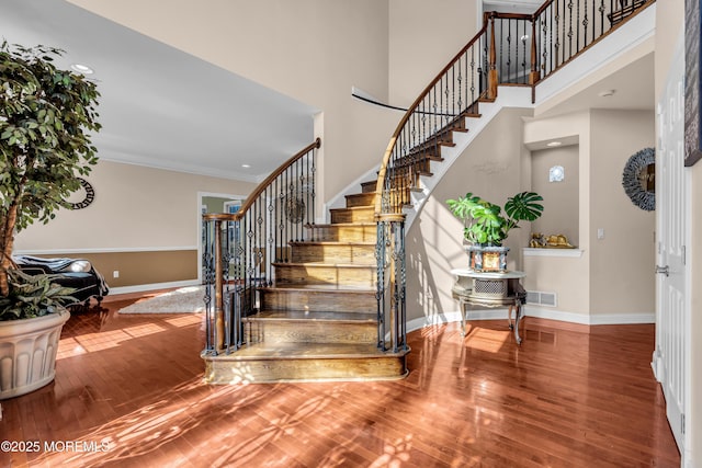 stairs with wood finished floors, visible vents, and baseboards