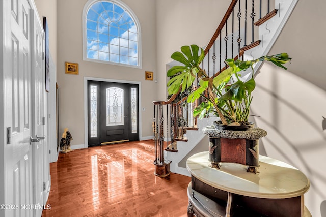 entrance foyer featuring a high ceiling, stairway, wood finished floors, and baseboards