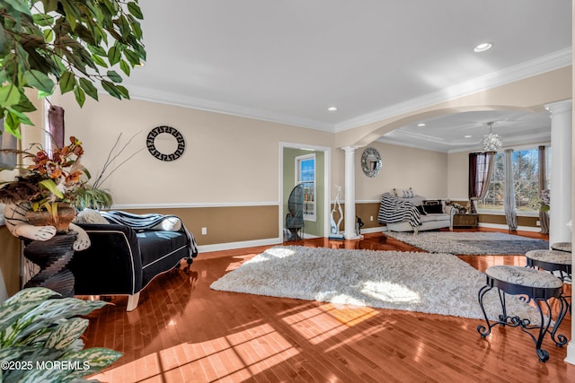 living room with decorative columns, crown molding, arched walkways, and wood finished floors