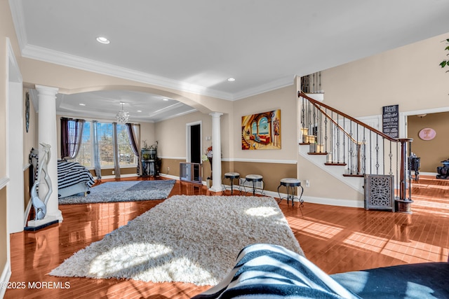 living area with ornate columns, stairway, ornamental molding, wood finished floors, and baseboards