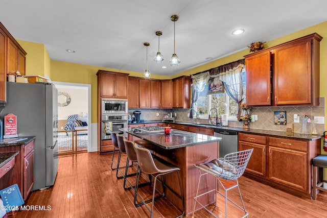 kitchen featuring a breakfast bar, a kitchen island, hanging light fixtures, appliances with stainless steel finishes, and dark stone countertops