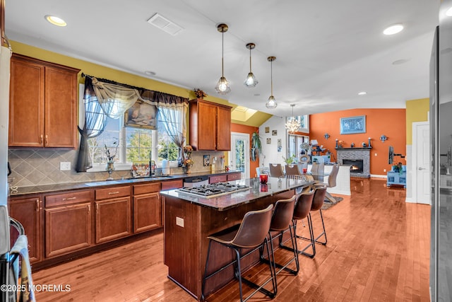 kitchen featuring a center island, pendant lighting, light wood-style floors, a sink, and a kitchen breakfast bar