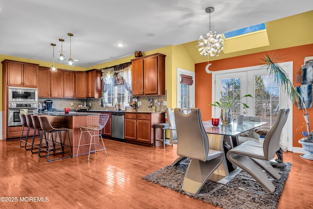 kitchen with stainless steel appliances, a kitchen island, decorative light fixtures, and a kitchen breakfast bar