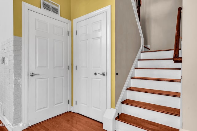 stairs with visible vents and wood finished floors