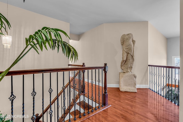 hall with wood finished floors, an upstairs landing, and baseboards