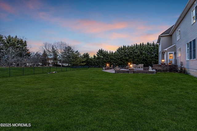 yard at dusk featuring an outdoor fire pit, a patio area, and fence private yard