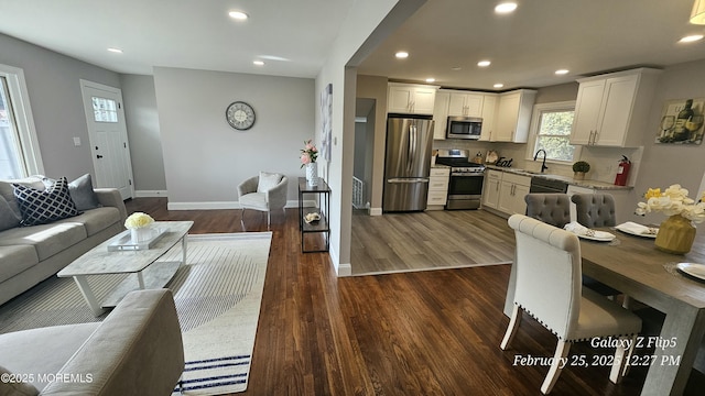 living room with dark wood-type flooring, recessed lighting, and baseboards