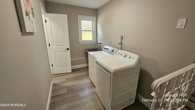 laundry area with light wood finished floors, a sink, laundry area, independent washer and dryer, and baseboards