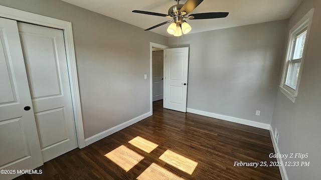 unfurnished bedroom with a closet, dark wood-style flooring, ceiling fan, and baseboards