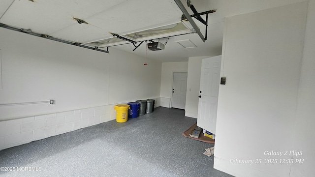 garage featuring concrete block wall and a garage door opener