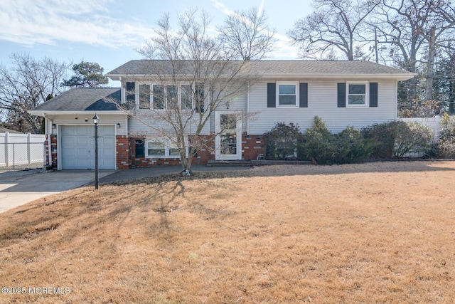 bi-level home with a garage, brick siding, fence, concrete driveway, and a front lawn