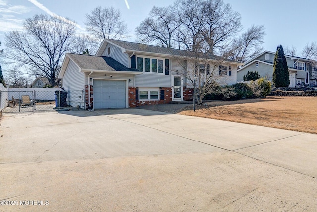 bi-level home with a gate, brick siding, driveway, and an attached garage