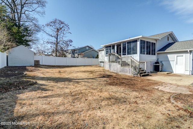 rear view of house featuring a sunroom, fence, and a lawn