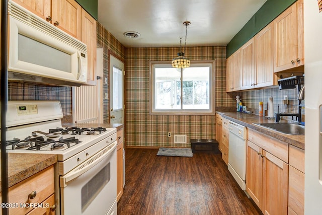 kitchen with white appliances, light brown cabinets, hanging light fixtures, and visible vents