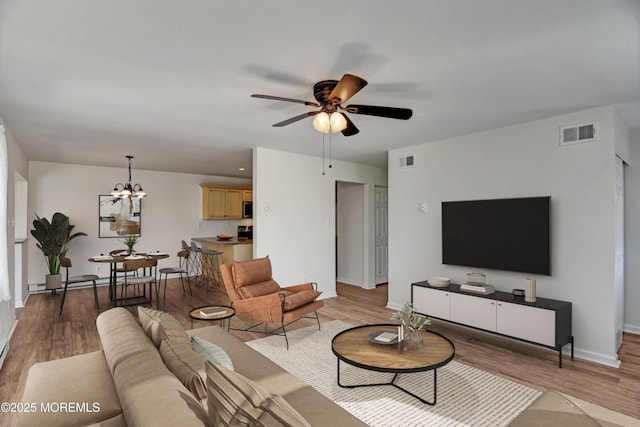 living room with light wood-style floors, visible vents, and baseboards