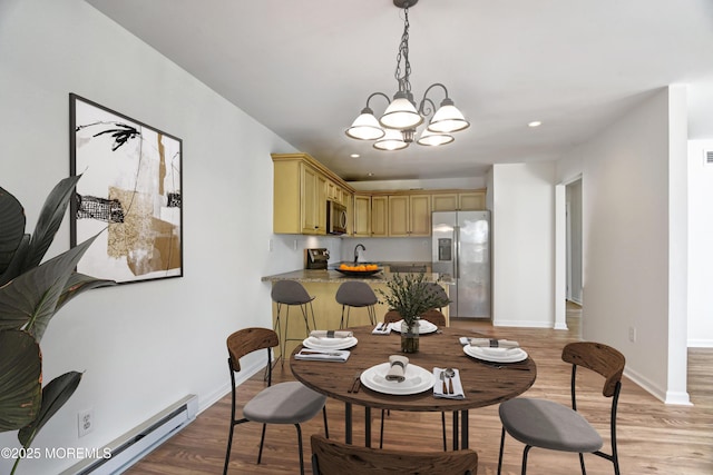 dining area featuring recessed lighting, baseboard heating, light wood-style floors, a chandelier, and baseboards