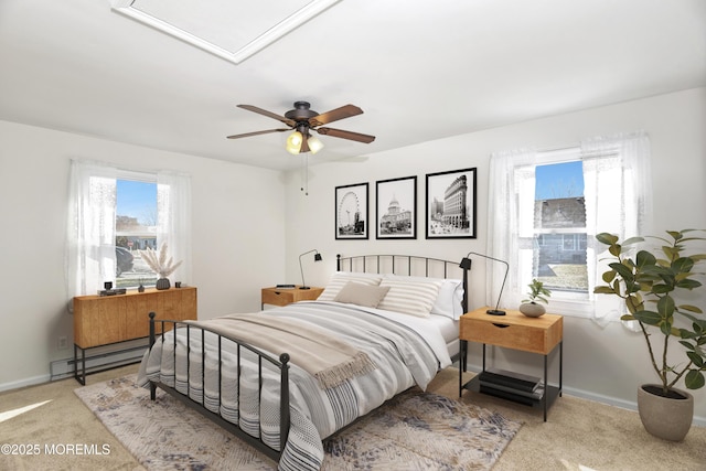 carpeted bedroom with a baseboard heating unit, ceiling fan, and baseboards