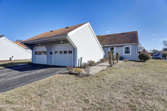 exterior space with a garage, a yard, and aphalt driveway