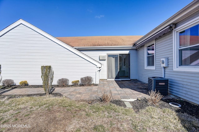 entrance to property featuring a patio, a lawn, and central AC unit