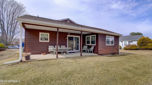 back of property featuring a patio area, a lawn, and roof with shingles